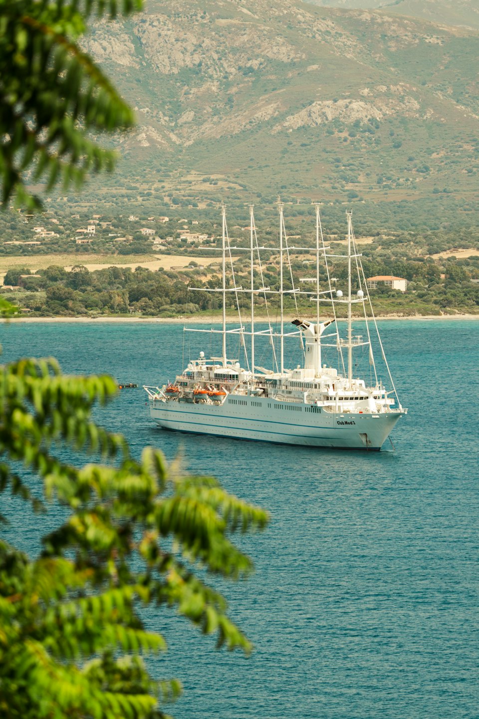 Plachetnice Club Med 2 proplouvá kolem bujné pobřežní krajiny.